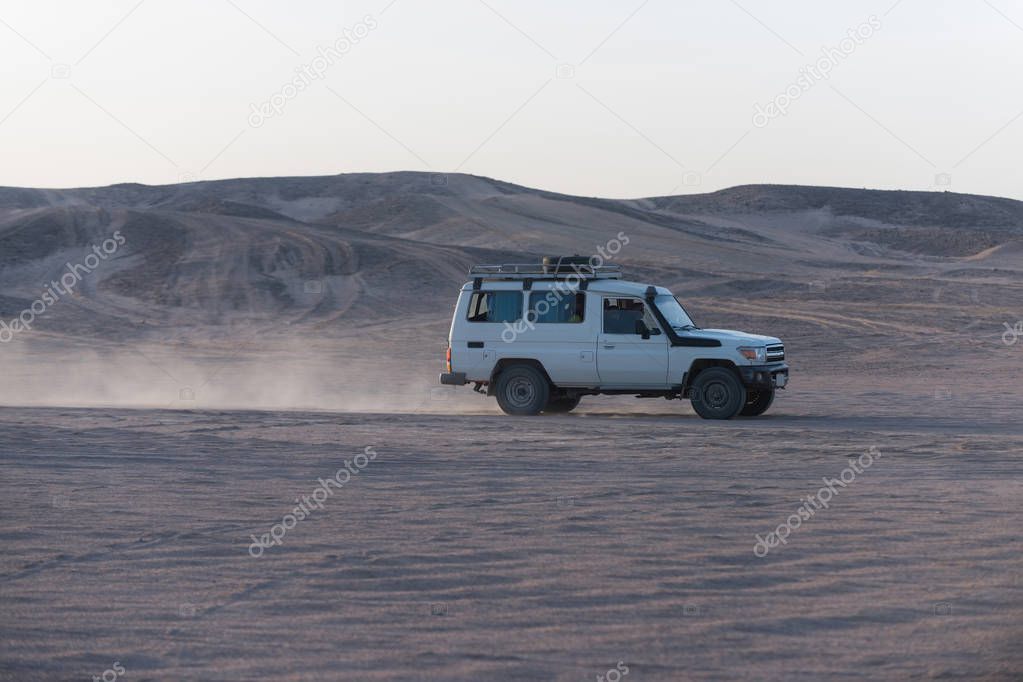 White jeep car driving on desert surface in sand dune