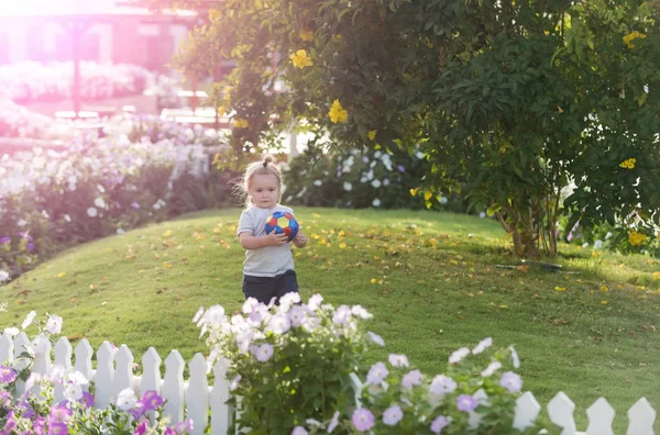 Ładny chłopczyk szczęśliwy gry z piłką na zielonej trawie — Zdjęcie stockowe