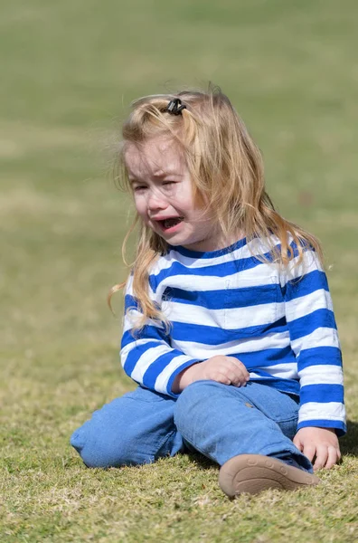 Infeliz lindo bebé niño sentado en verde hierba en parque —  Fotos de Stock