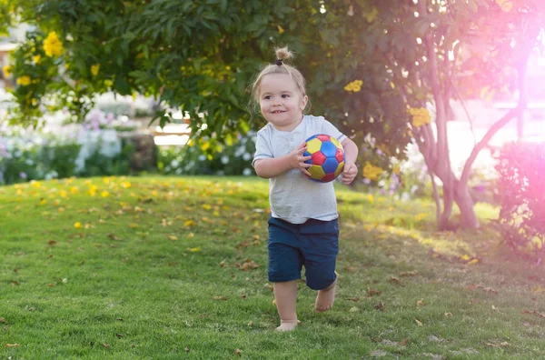 Feliz lindo bebé jugando con la pelota en la hierba verde — Foto de Stock