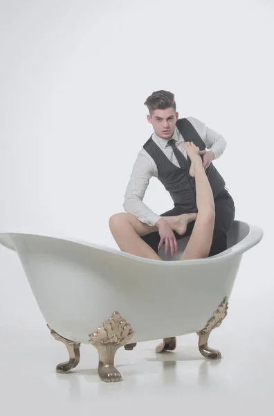 Красивый мужчина расслабляется с сексуальными голыми женскими ногами в ванной — стоковое фото