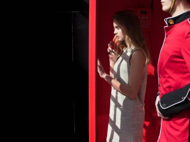 Güzel kız kırmızı telefon kutusunda telefonda konuşuyor