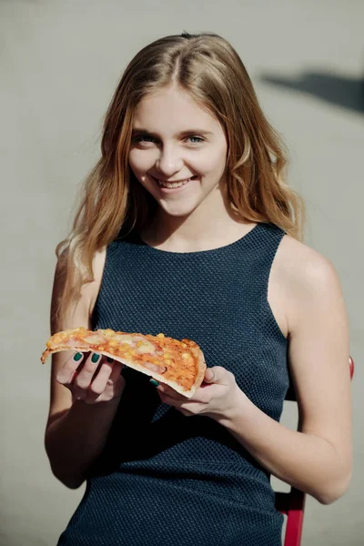 Feliz chica bonita sonriendo con un pedazo de pizza sabrosa — Foto de Stock
