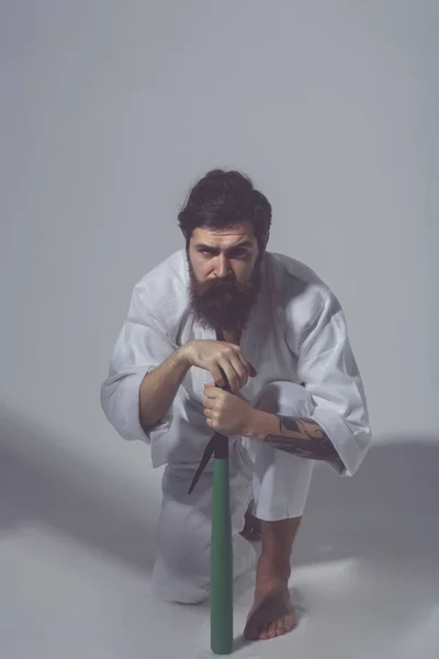 Skäggiga allvarliga karate man i kimono med gröna basebollträ — Stockfoto