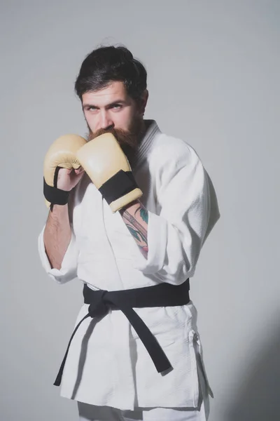 Skäggiga allvarliga karate man i kimono och boxning handskar — Stockfoto