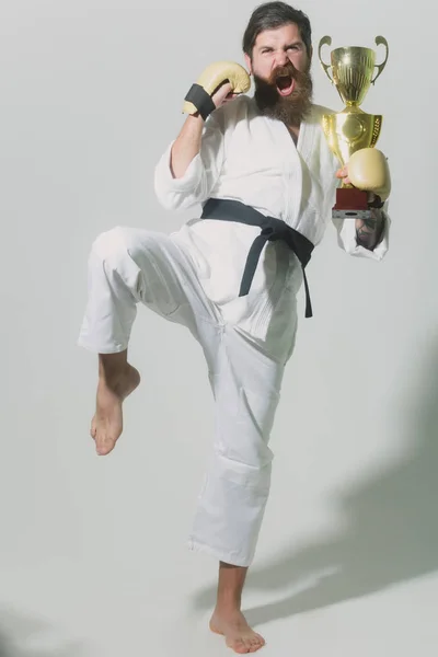 Bearded happy karate man in kimono, boxing gloves, champion cup — Stock Photo, Image