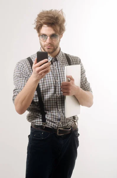 Vakava komea mies puhuu älypuhelimeen kannettavalla tietokoneella — kuvapankkivalokuva