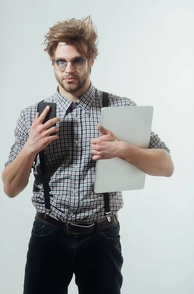Homem bonito em óculos nerd com smartphone e laptop — Fotografia de Stock