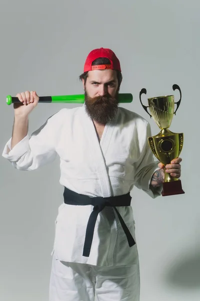 Bearded karate man in kimono, green baseball bat, champion cup — Stock Photo, Image