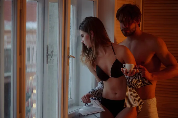 Сексуальная девушка с утюгом, чашка кофе и мужчина у окна — стоковое фото