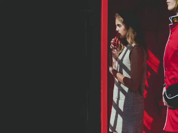 Güzel kız kırmızı telefon kutusunda telefonda konuşuyor — Stok fotoğraf