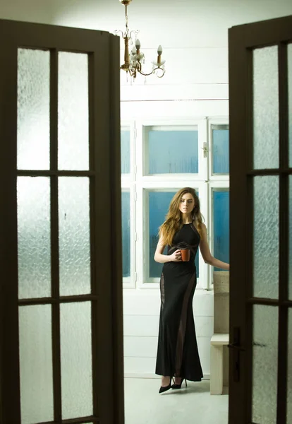 Pretty girl in black dress through open doors — Stock Photo, Image