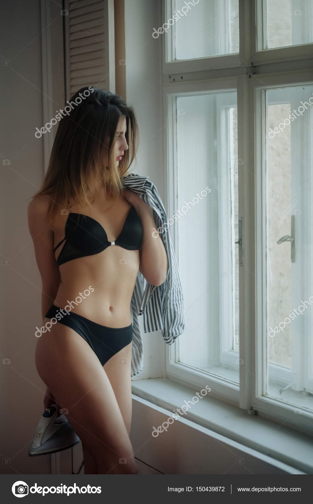 Sexy girl with iron and shirt in lingerie at window Stock Photo by ©Tverdohlib 150439872