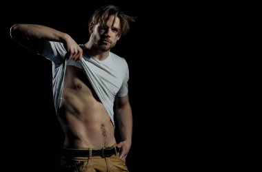 Beyaz tişörtlü yakışıklı adam seksi, kaslı gövdesini gösteriyor.