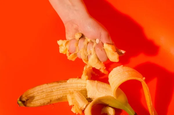 Female hand squeezing juice or squash from banana — Stock Photo, Image