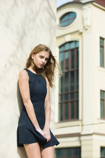 Menina bonita em vestido preto na moda na parede do edifício — Fotografia de Stock