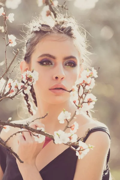 Pretty girl with fashionable makeup among spring blooming cherry flowers — Stock Photo, Image