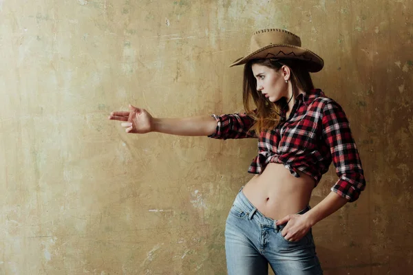 Chica bonita en elegante sombrero de vaquero que muestra la pistola de dedo —  Fotos de Stock