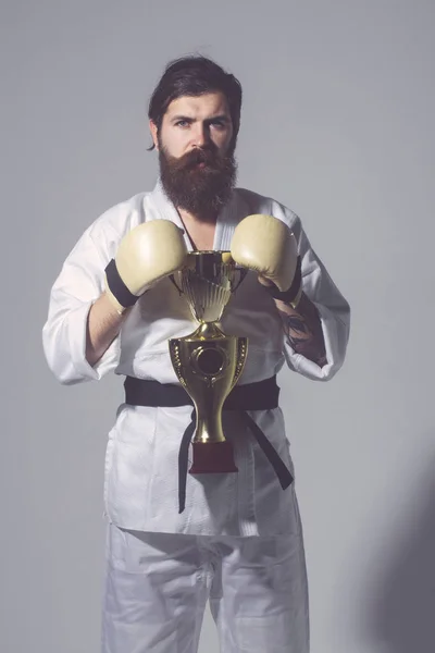 Bearded karate man in kimono, boxing gloves, champion cup — Stock Photo, Image