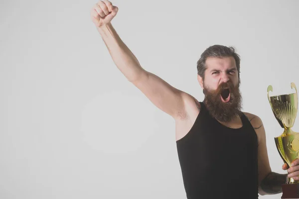 Bärtiger glücklicher Mann hält goldenen Meisterpokal auf grauem Hintergrund — Stockfoto