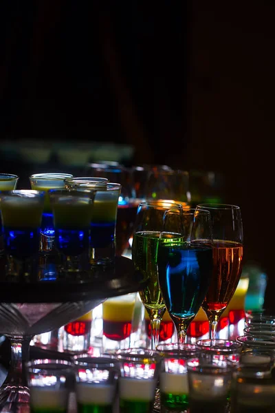 Kleurrijke cocktails en gelaagde schoten op aanrecht — Stockfoto