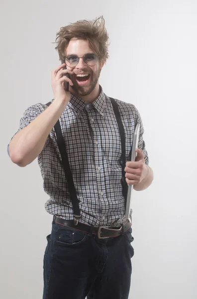 Onnellinen komea mies puhuu älypuhelimella kannettavalla tietokoneella — kuvapankkivalokuva