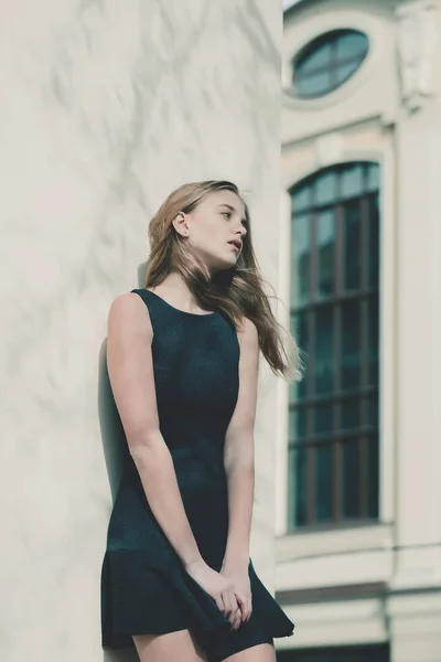 세련 된 블랙 드레스 건물 벽에 예쁜 여자 — 스톡 사진