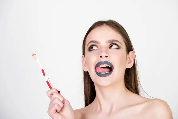 Chica con dientes frenos y cepillo, tiene maquillaje de moda — Foto de Stock