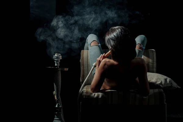 Сексуальна дівчина з голим тілом курить кальян у джинсах — стокове фото