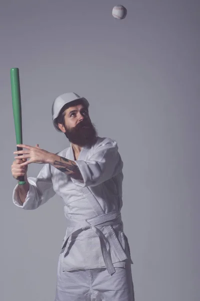 Karate bebaarde man in kimono, helm met honkbalknuppel, bal — Stockfoto