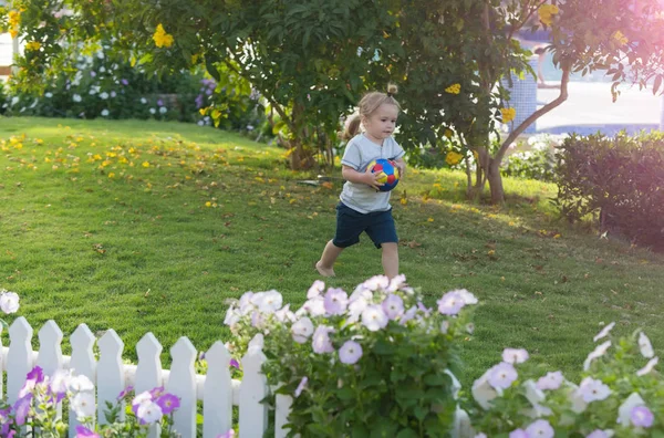 Милый счастливый мальчик бросает красочный мяч — стоковое фото
