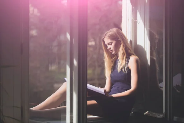 Söt flicka läsebok vid öppet fönster — Stockfoto