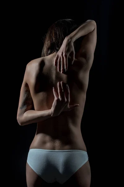 Kobieta cierpi z powodu bólu kręgosłupa, bóle pleców, stojąc nad czarnym tle — Zdjęcie stockowe