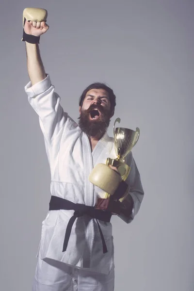 Γενειοφόρος άνθρωπος ευτυχισμένος καράτε κιμονό, γάντια του μποξ, πρωταθλητής Κύπελλο — Φωτογραφία Αρχείου