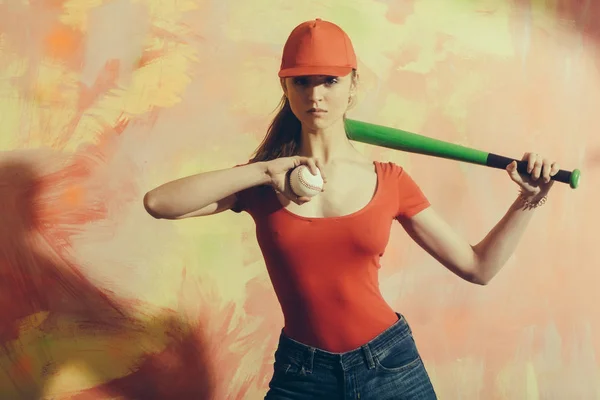 Красивая девушка в красной кепке с зеленой битой и мячом — стоковое фото