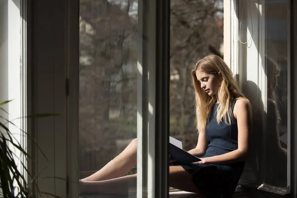 Söt flicka läsebok vid öppet fönster — Stockfoto