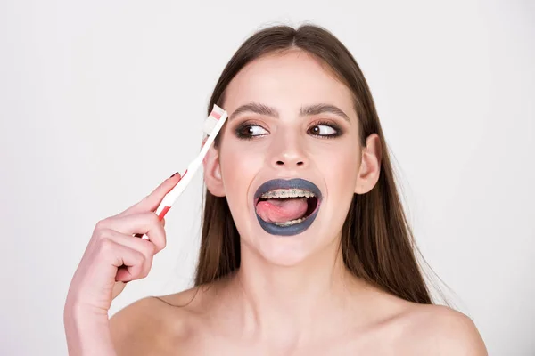 Girl with teeth braces and brush, has fashionable makeup — Stock Photo, Image