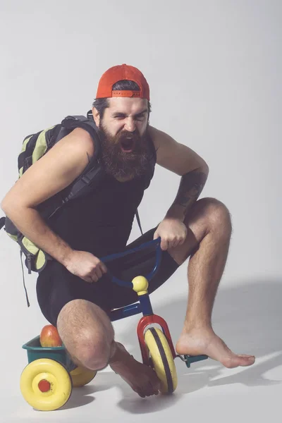Bearded shouting man with bag, apple on bicycle toy — Stock Photo, Image