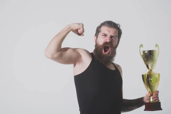 Bärtiger glücklicher Mann hält goldenen Meisterpokal auf grauem Hintergrund — Stockfoto