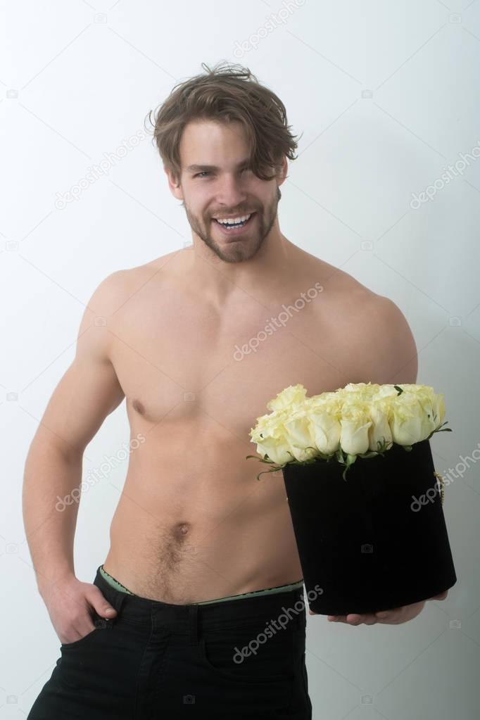 Smiling handsome man with roses in black present box
