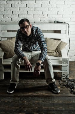 adam gözlük ve mikrofon ile bankta kareli gömlek