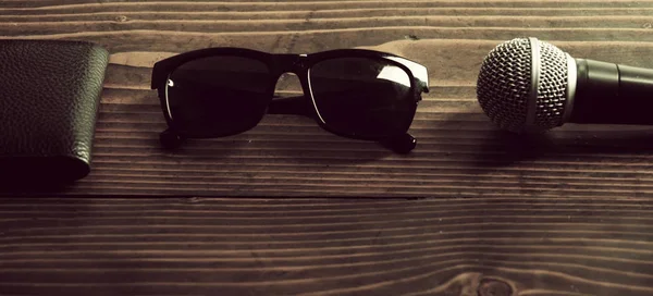 Skinnväska, fashionabla sommaren solglasögon och mikrofon på trä bakgrund — Stockfoto