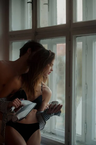 Сексуальна дівчина з залізом, чашкою кави і чоловіком у вікні — стокове фото