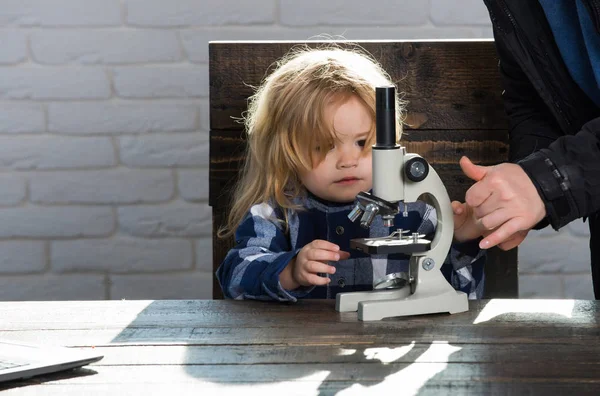 Мальчик студент учится на рабочем месте с микроскопом, ноутбук — стоковое фото