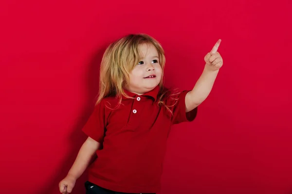 Liten glad pojke pekande finger på rosa bakgrund — Stockfoto