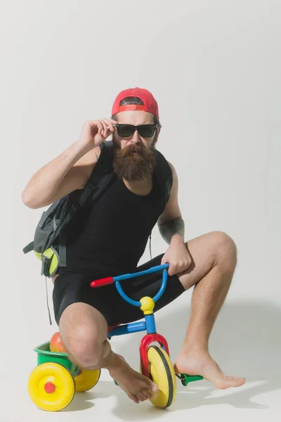 Homem surpreso barbudo com saco, maçã no brinquedo da bicicleta — Fotografia de Stock