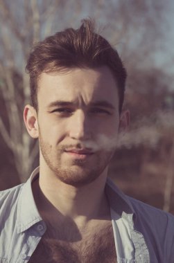 Tıraşsız yüzü buharı bulut burun exhaling yakışıklı adam