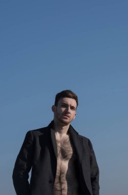 Seksi erkek poz çıplak, kıllı gövde paltoyla düğmelerini aç