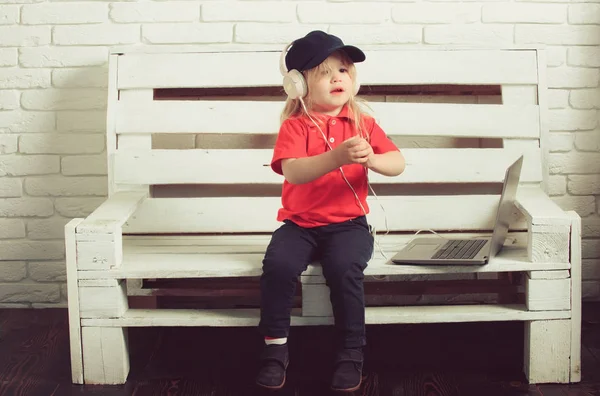 Kleiner Junge im Headset hört Musik, Hörbuch, arbeitet auf Laptops — Stockfoto