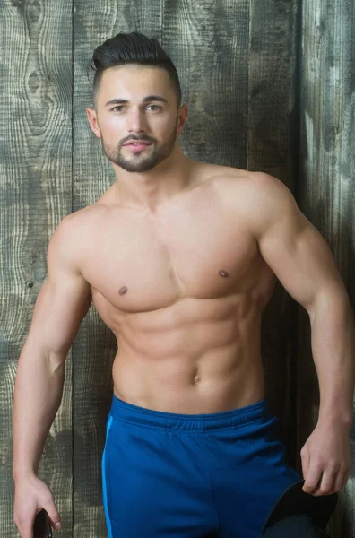 Handsome man posing in blue pants with phone and cap